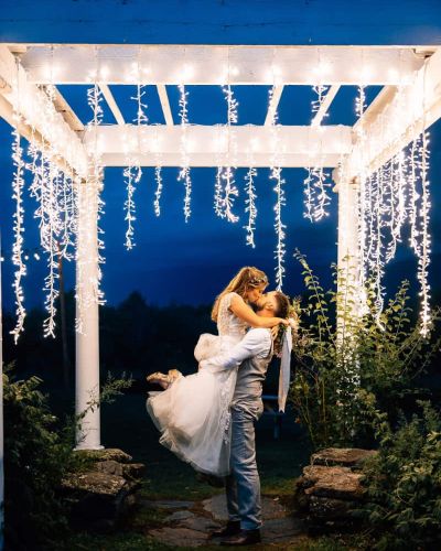 Bride and Groom kiss under pergola lighting